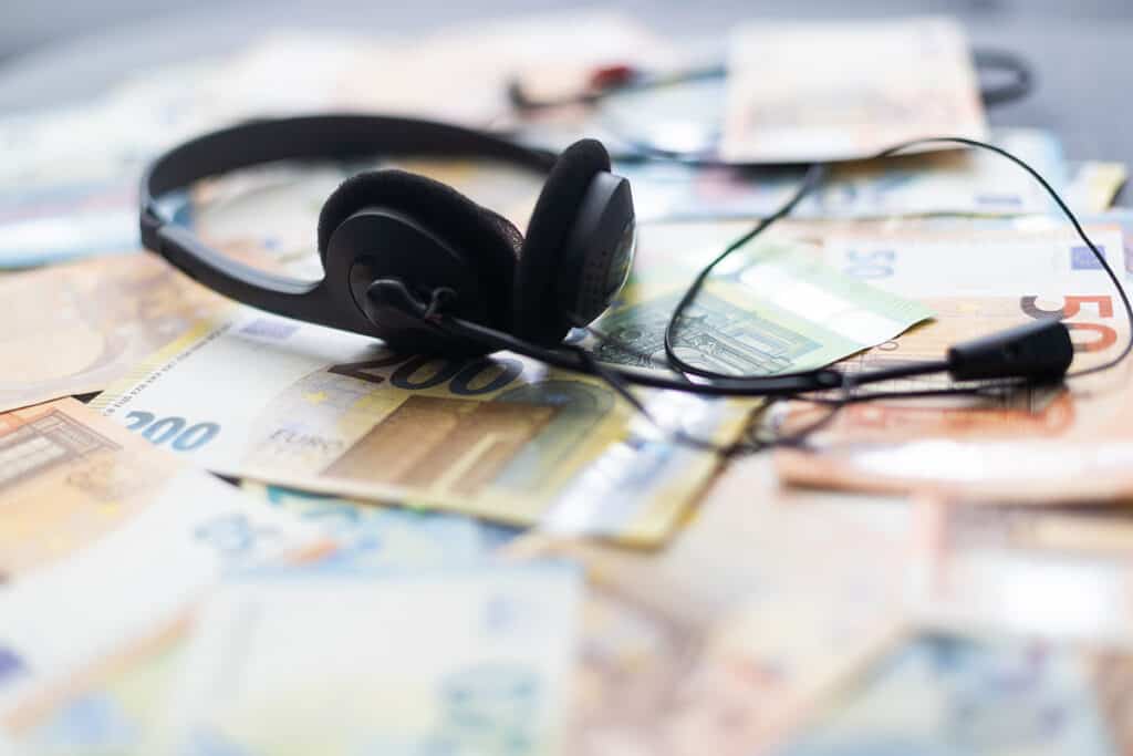 A contact center headset resting on a pile of money.
